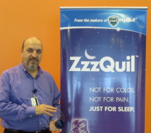 Ashraf Traboulsi standing next to a ZzzQuil banner